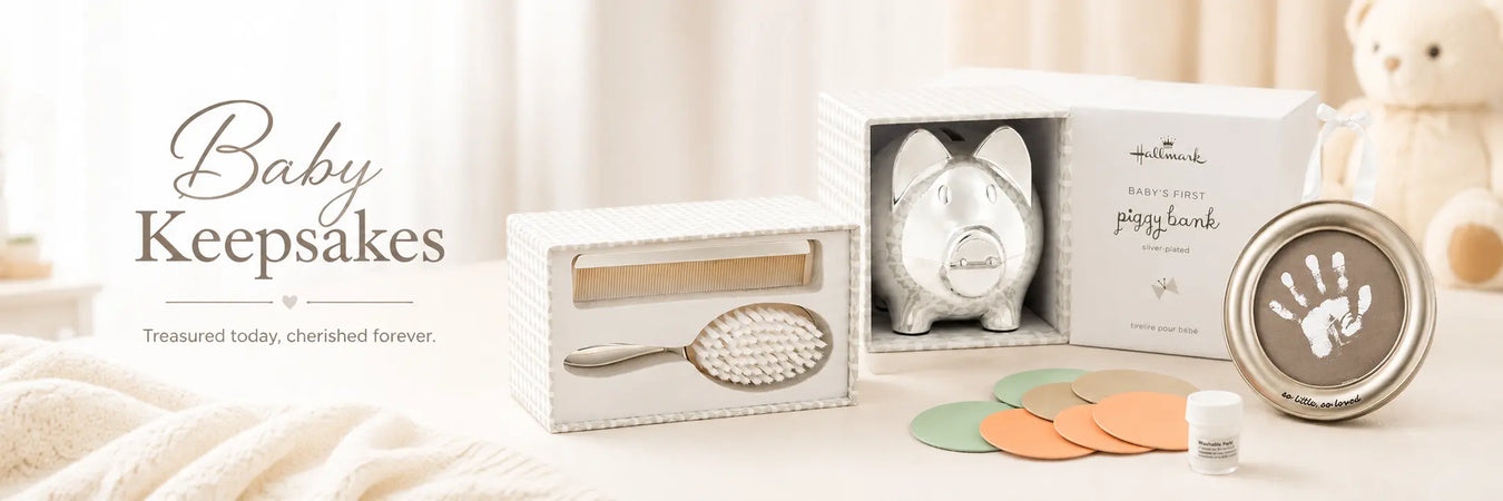 Baby Keepsakes collection banner featuring a silver piggy bank, baby brush and comb set, handprint keepsake frame, and pastel nursery accents.