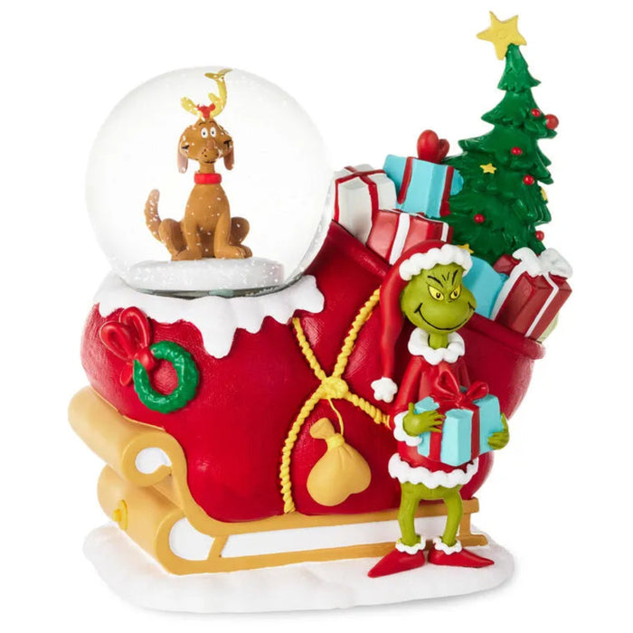 Decorative Christmas scene with a sleigh, Grinch, and snow globe on a white background