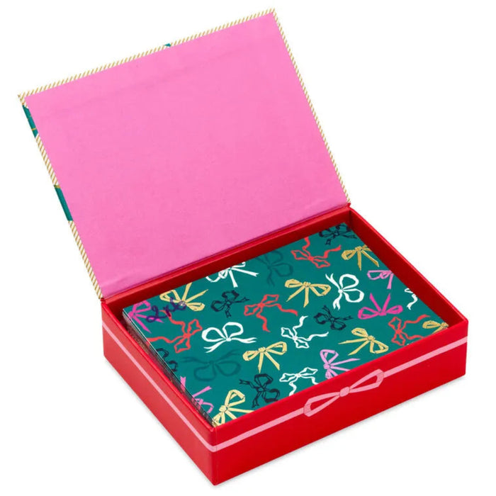 Open red box with pink interior containing a green card with colorful bow pattern on a white background