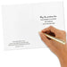 Hand holding a gold pen over a white card with text