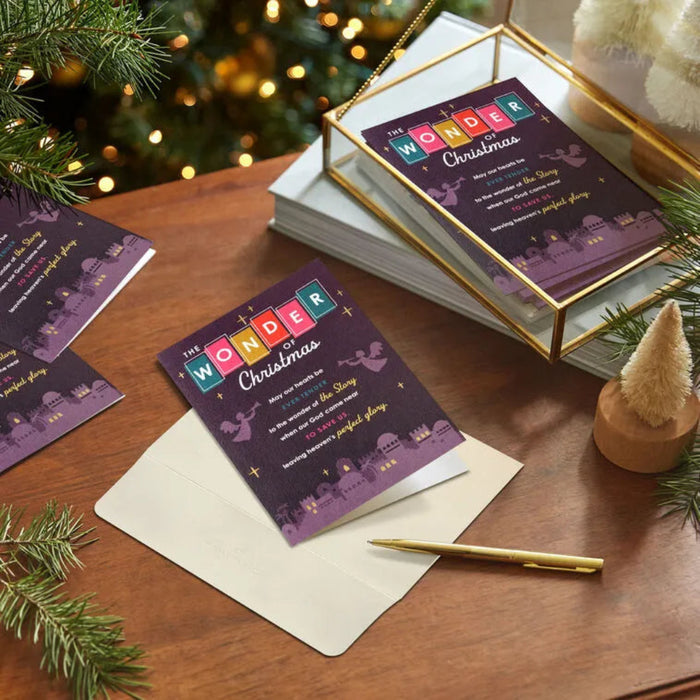 Christmas cards with colorful text on a wooden surface with festive decorations.