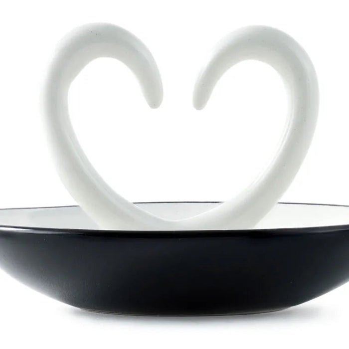  close up of Ring dish ceramic with arms that shape a heart. trinket dish on a white background. 