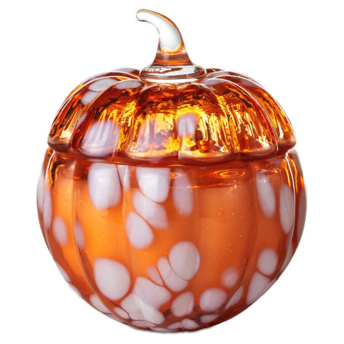 Glass pumpkin candle with white speckles on a white background
