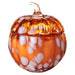 Glass pumpkin candle with white speckles on a white background