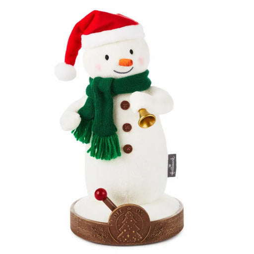 Snowman plush toy with a red hat, green scarf, and bell  that plays a holiday jingle on a white background