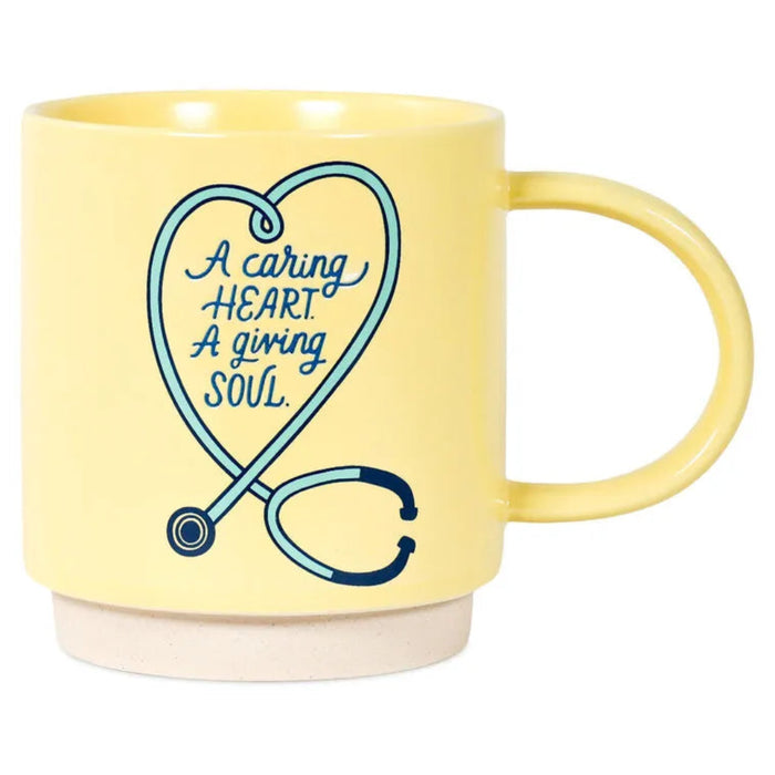 Yellow mug with a stethoscope design and text 'A caring HEART A giving SOUL' on a white background