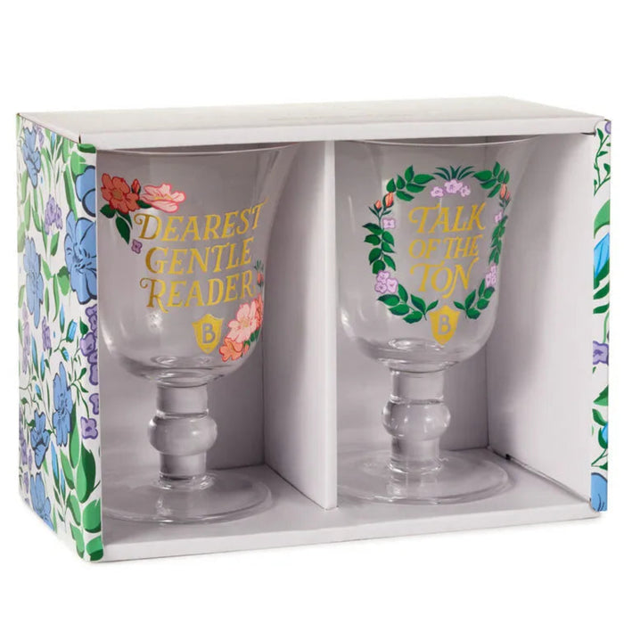 Boxed set of two Bridgerton-themed goblet glasses displayed in a floral-patterned gift box, each clear glass featuring gold lettering and pastel floral designs, photographed on a white background.”