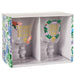 Boxed set of two Bridgerton-themed goblet glasses displayed in a floral-patterned gift box, each clear glass featuring gold lettering and pastel floral designs, photographed on a white background.”