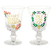 Two clear Bridgerton goblet glasses shown side by side on a white background, one reading ‘Dearest Gentle Reader’ and the other ‘Talk of the Ton,’ both decorated with gold lettering and floral wreath designs.”