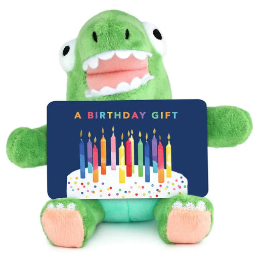 Green plush toy holding a birthday gift card with candles on a white background