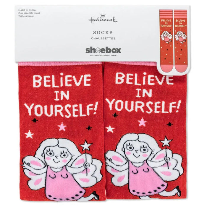 Red socks with angel design and 'Believe in Yourself!' text, displayed in packaging.