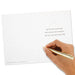 Hand holding a gold pen over a white card with text on a white background