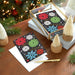 Holiday greeting cards with colorful snowflakes on a wooden table with Christmas decorations.