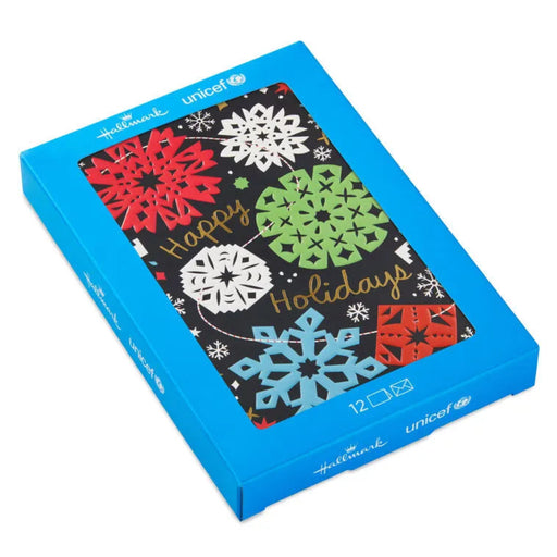 Box of 'Happy Holidays' cards with colorful snowflakes on a black background, featuring Unicef branding.