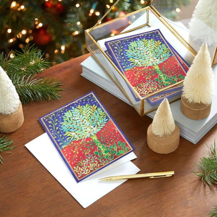 Colorful greeting cards with a Christmas tree design on a wooden table with decorative items.