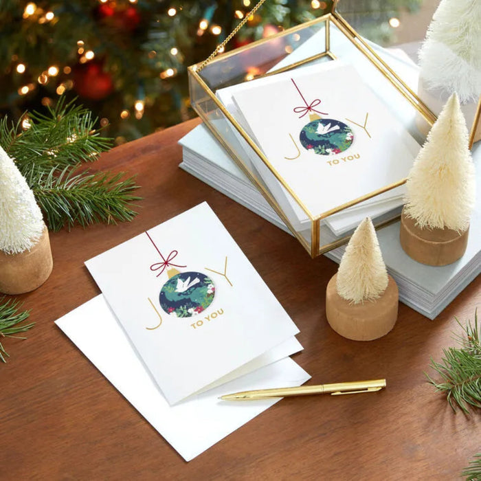 Stack of Christmas cards with decorative elements on a wooden surface.