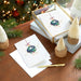 Stack of Christmas cards with decorative elements on a wooden surface.