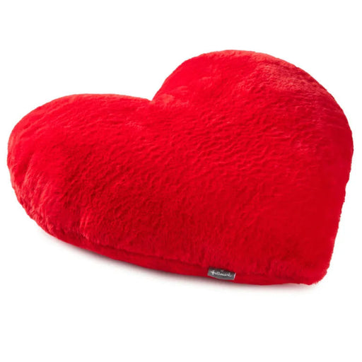 Side view of a soft red heart-shaped plush pillow with fluffy texture and rounded edges.