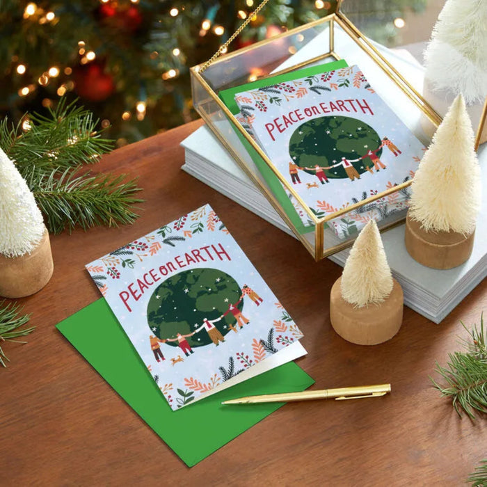 Christmas cards with 'Peace on Earth' design on a wooden table with festive decorations.