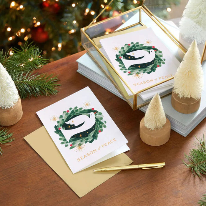 Christmas cards with penguin design on a wooden table with festive decorations.