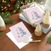 Christmas-themed greeting cards with a tree design on a wooden table with decorative items.