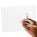 Hand holding a gold pen over a white card with text and a butterfly illustration.