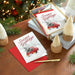 Stack of Christmas cards with 'Season's Greetings' on a wooden table with festive decorations.