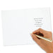 Hand holding a gold pen over a white card with text on a white background