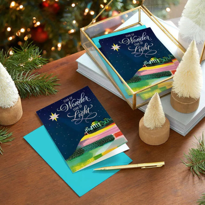 Christmas cards with 'Star of Wonder, Star of Light' design on a wooden table with festive decorations.