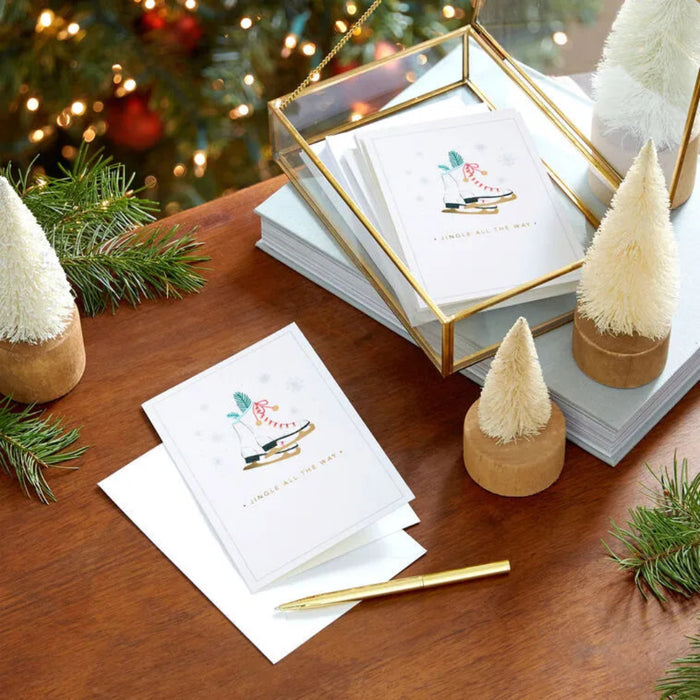 Stack of greeting cards with decorative Christmas trees and a pen on a wooden surface.