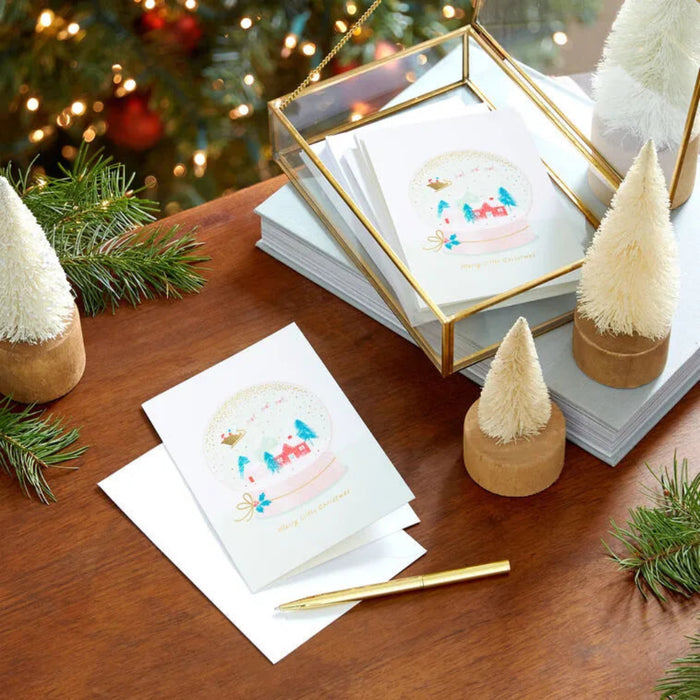 Holiday card set with decorative trees and pen on a wooden surface.