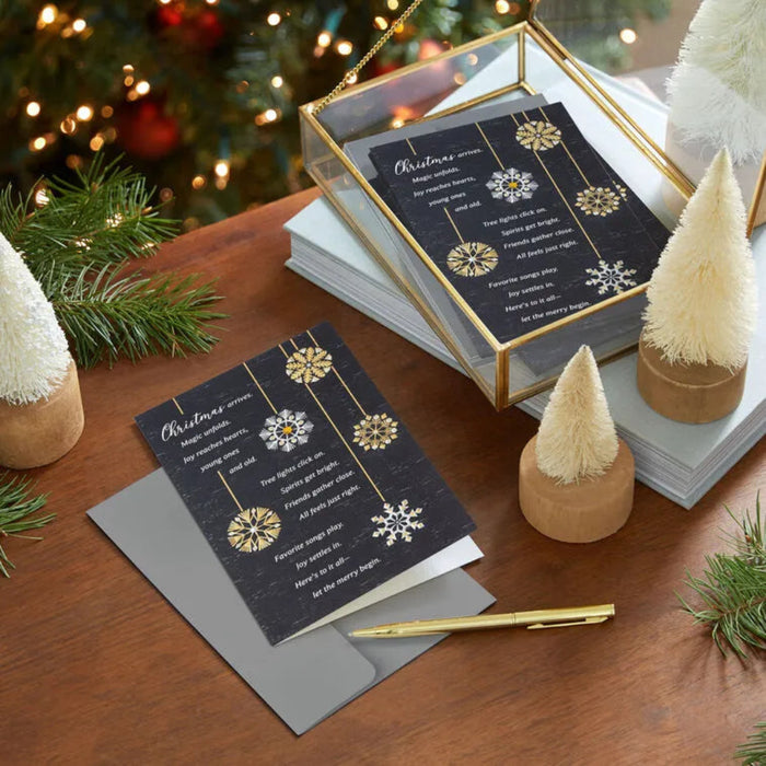 Decorative Christmas cards with gold and silver snowflake designs on a wooden surface with festive background.