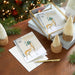 Stack of Christmas cards with deer design on a wooden table with festive decorations.