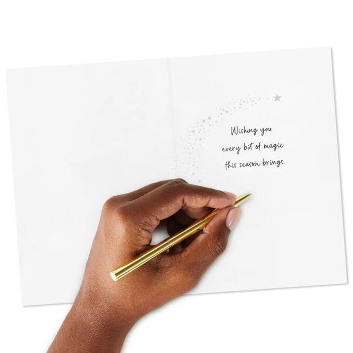 Hand holding a gold pen over a card with a message on a white background