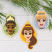 Three princess-themed  mini Christmas ornaments hanging on a  Christmas tree branch.