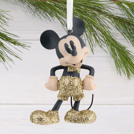 Mickey Mouse ornament with gold shorts hanging on a Christmas tree.