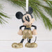 Mickey Mouse ornament with gold shorts hanging on a Christmas tree.