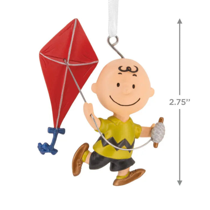 Ornament of Charlie Brown character with a red kite and measurement details on a white background
