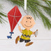 Ornament of Charlie Browncharacter holding a red kite against a white background with greenery.