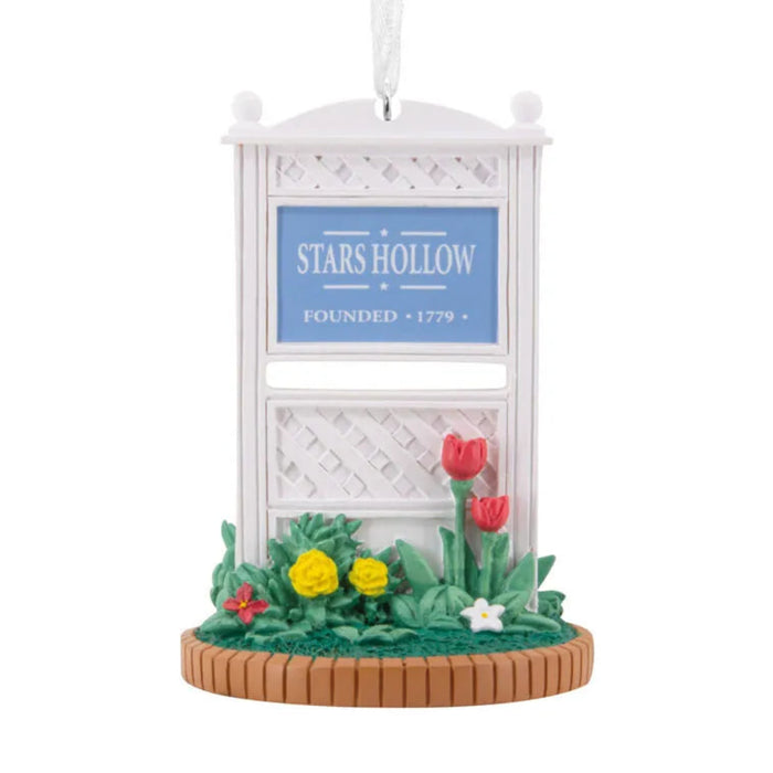 Decorative ornament with 'Stars Hollow' sign and flowers on a white background