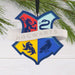 Hogwarts Houses Crest Shield Ornament  hanging off a pine branch on a white background .