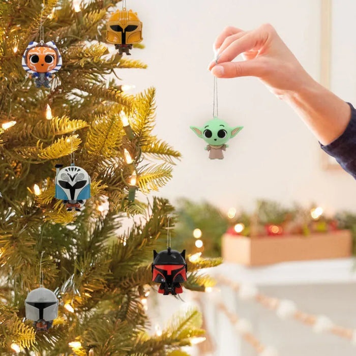 Decorative Christmas  Star wars themed ornaments on a tree with a hand reaching to hang one. One chosen at random 