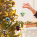 Decorative Christmas  Star wars themed ornaments on a tree with a hand reaching to hang one. One chosen at random 