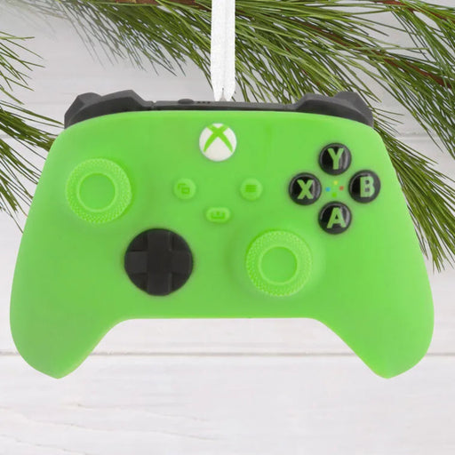 Green Xbox controller ornament with Christmas tree branches in the background