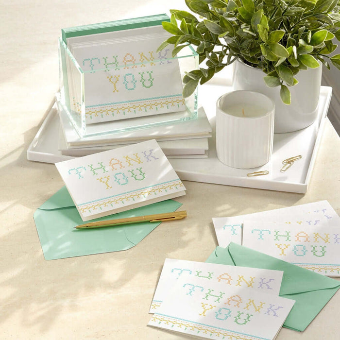 Set of 'Thank You' cards with matching envelopes on a table with a plant and candle.