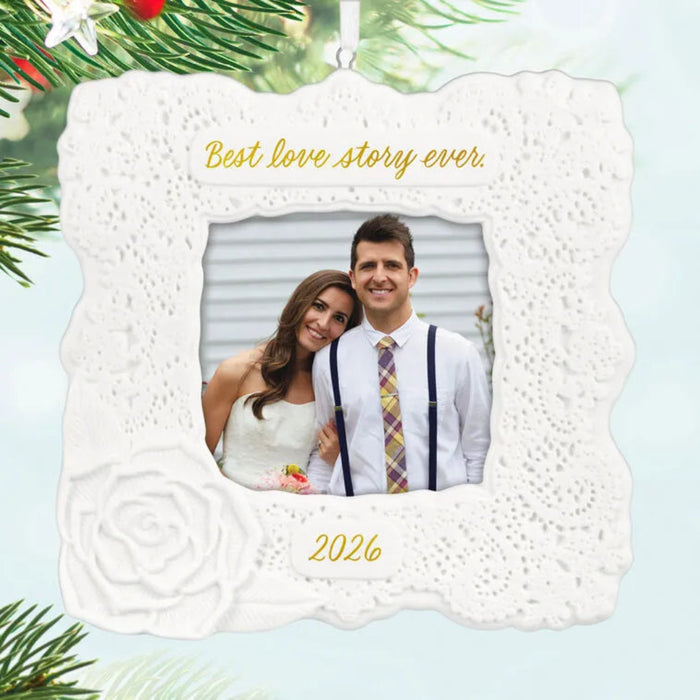 Decorative photo ornament with a couple's picture and 'Best love story ever' text, surrounded by Christmas tree branches.