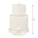 Two-tiered white decorative cake ornament with '2026' on a white background