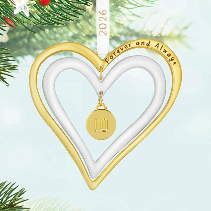 Heart-shaped ornament with gold border and pendant, hanging against a green Christmas tree background.