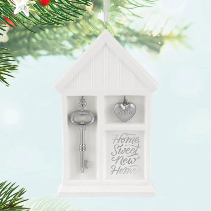 Decorative ornament with key and heart shaped tag, 'Home Sweet New Home' text, on a Christmas tree.