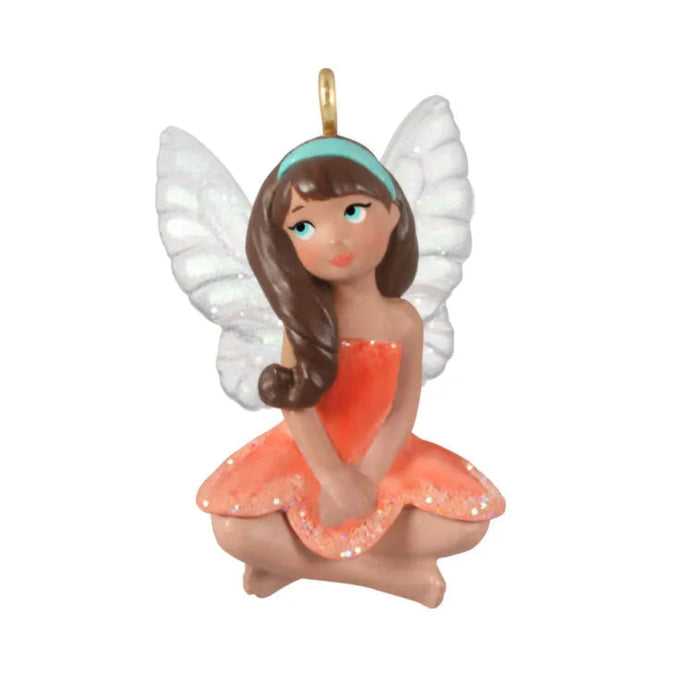Fairy figurine with white wings and an orange dress on a white background